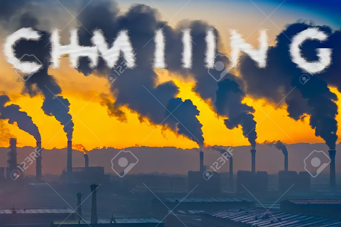 Evening view of the industrial landscape of the city with smoke emissions from chimneys at sunset- global warming