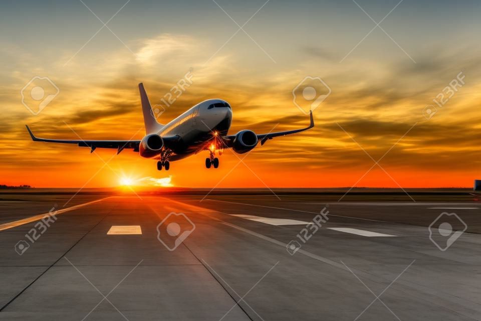 Airplane take off on a runway in the evening during a bright sunset.