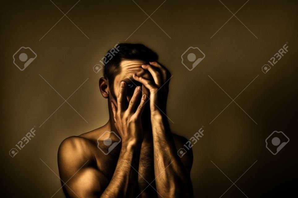 dramatic portrait of a guy, hands in the face