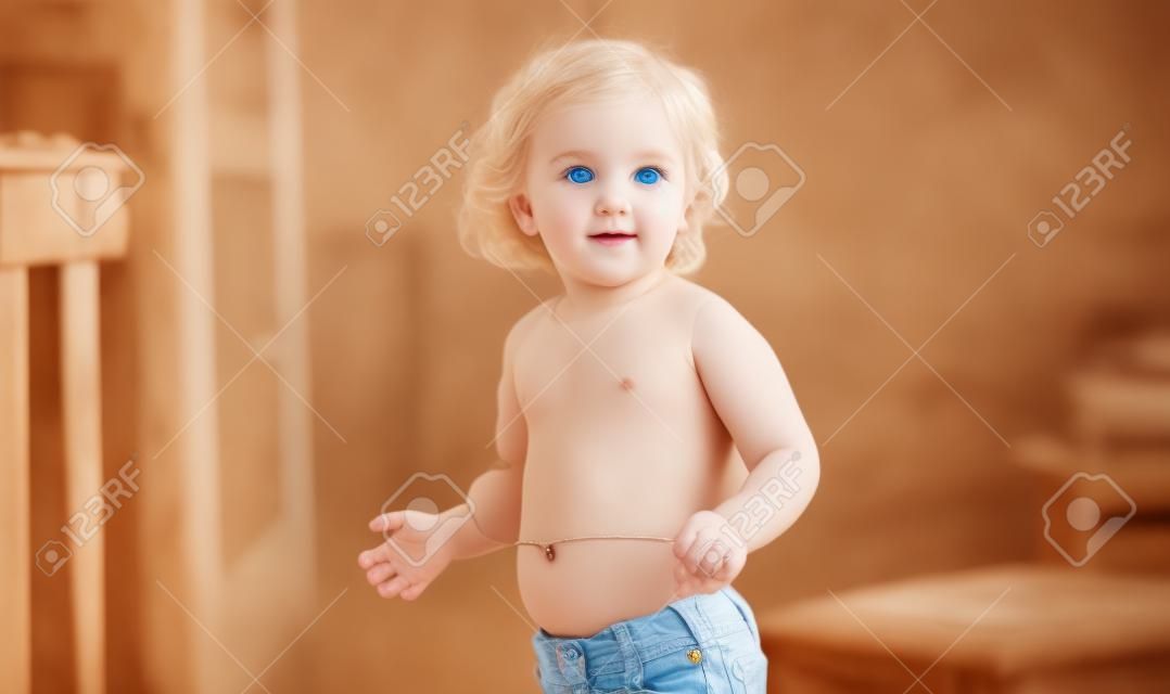 Piękna blondynka dziecko o niebieskich oczach stojących pokazując pępek w domu.