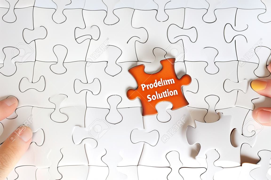 Hand holding piece of jigsaw puzzle with word PROBLEM SOLUTION. Selective focus