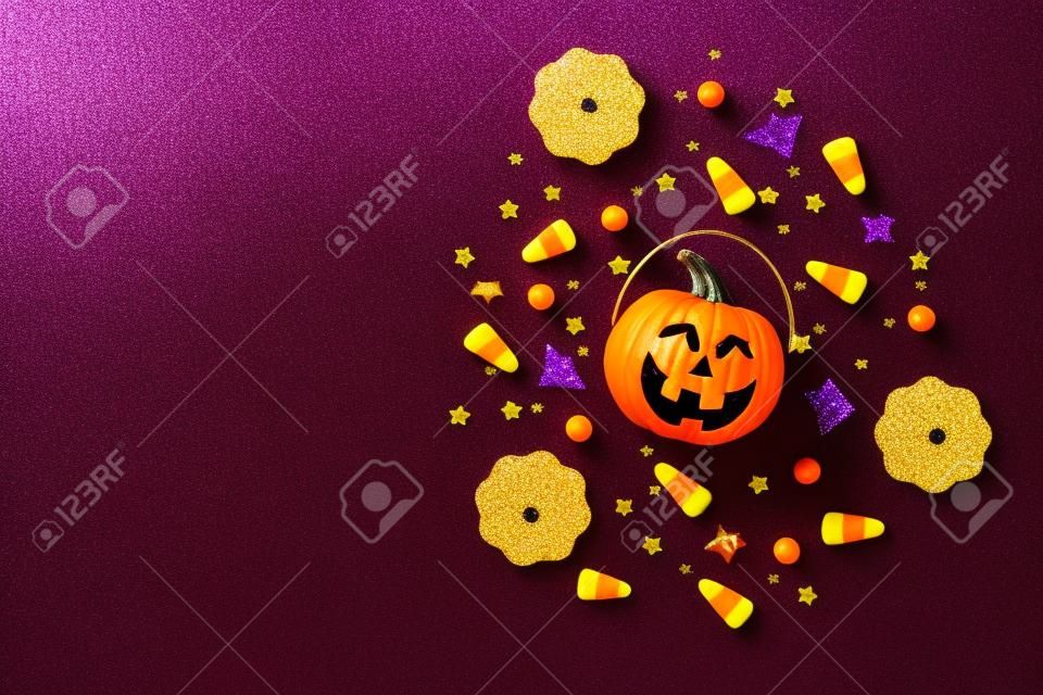 Foto de vista superior de decoraciones de halloween cesta de calabazas maíz dulce lentejuelas negras estrellas doradas murciélago siluetas de telaraña sobre fondo violeta aislado con copyspace