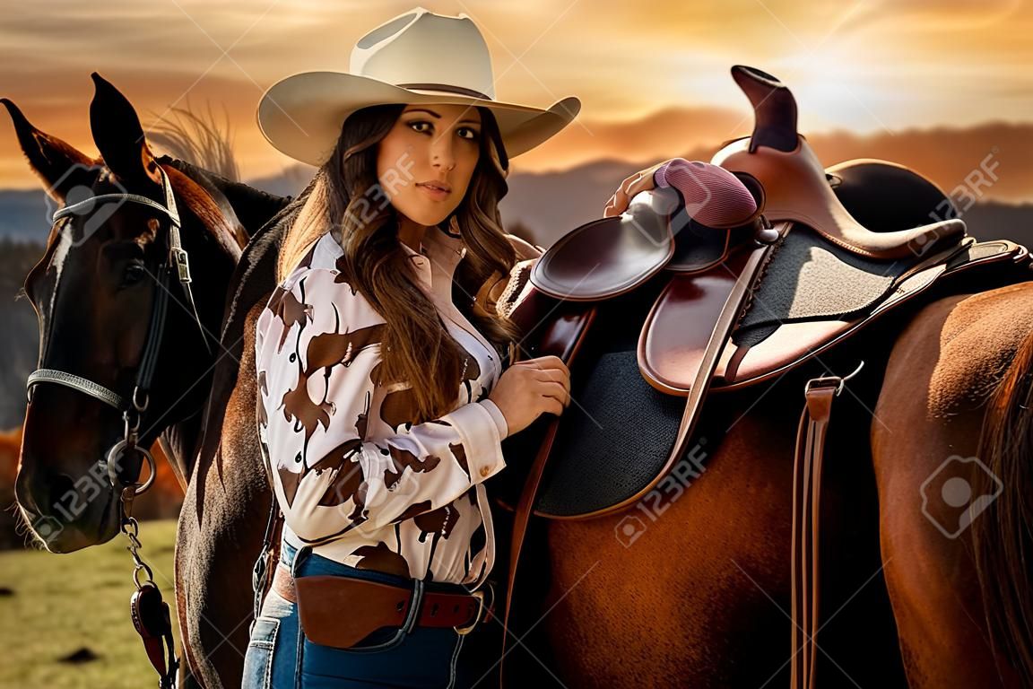 A beautiful brunette cowgirl poses with her horse before riding in the country