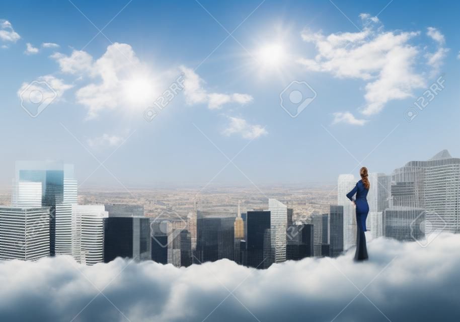 Imprenditrice in piedi con la schiena in cima alla collina e la visualizzazione città moderna