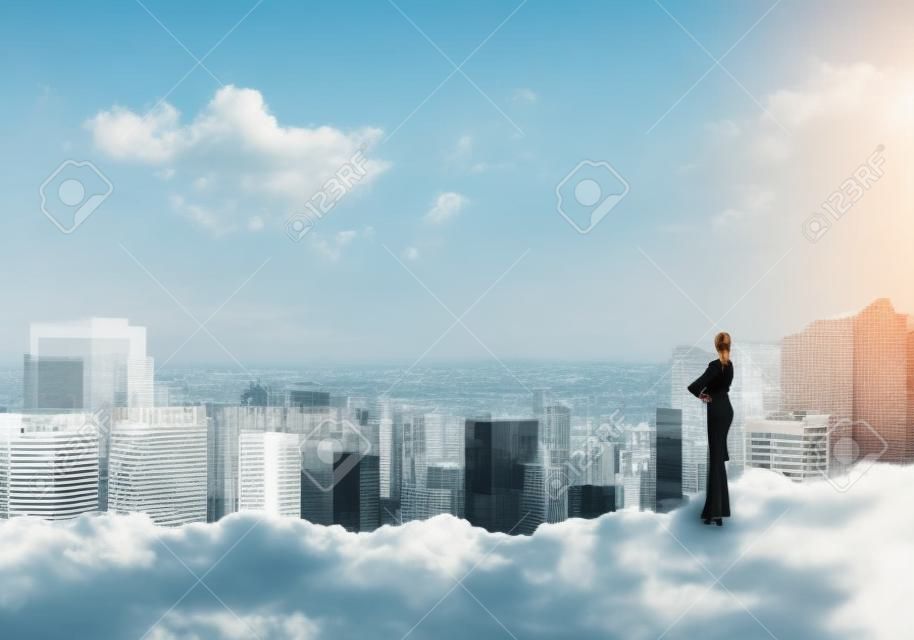Businesswoman standing with back on top of hill and viewing modern city