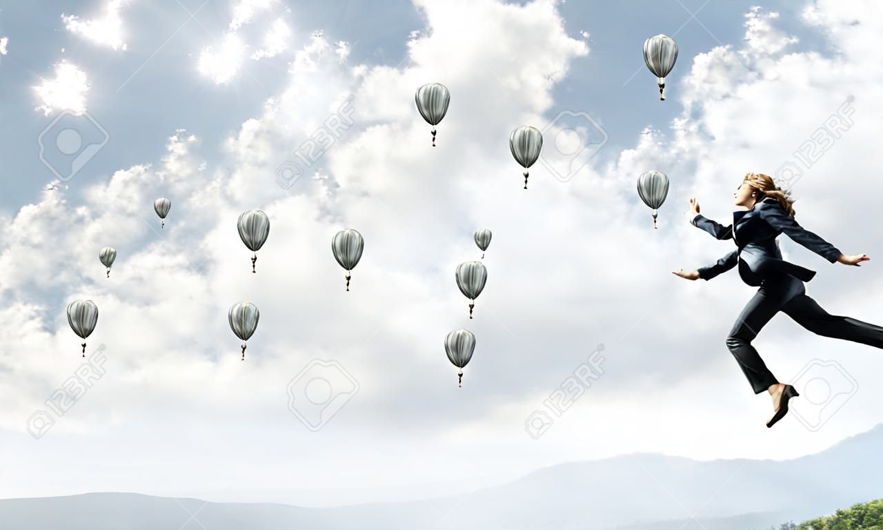 Attractive business woman in suit jumping in the air as symbol of active life position. Skyscape with flying balloons and nature view on background. 3D rendering.