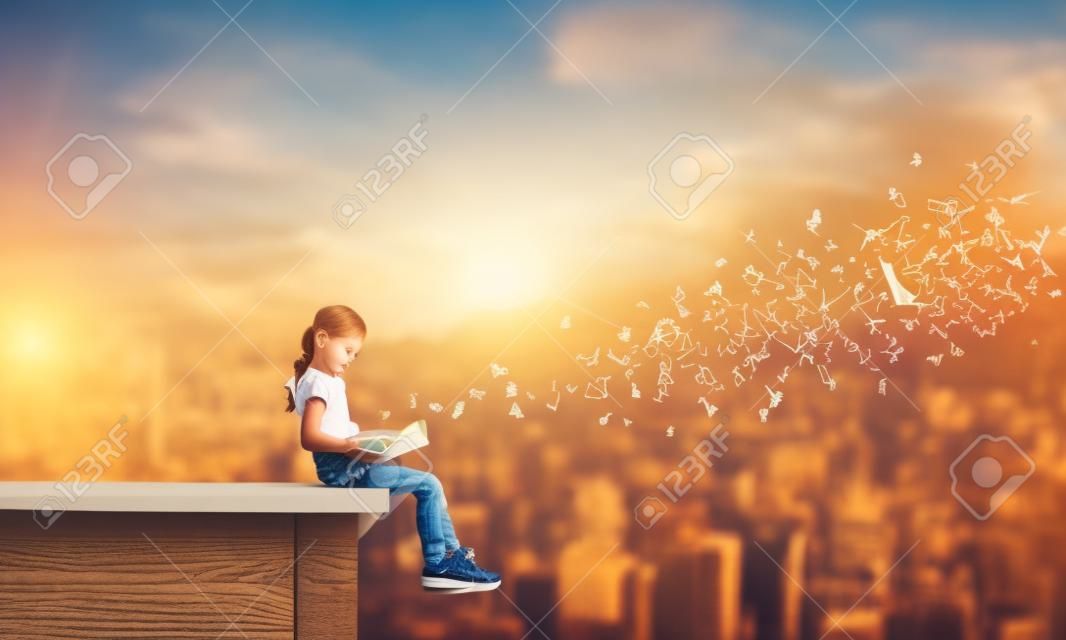 Słodka dziewczynka siedzi na dachu budynku, czyta książkę i litery latają w powietrzu