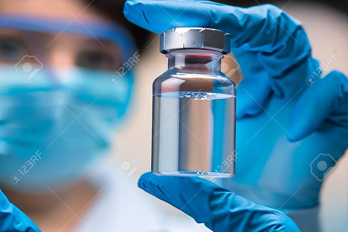 Doctor scientist with protective gloves and face mask holding vaccine medicine dose stock photo