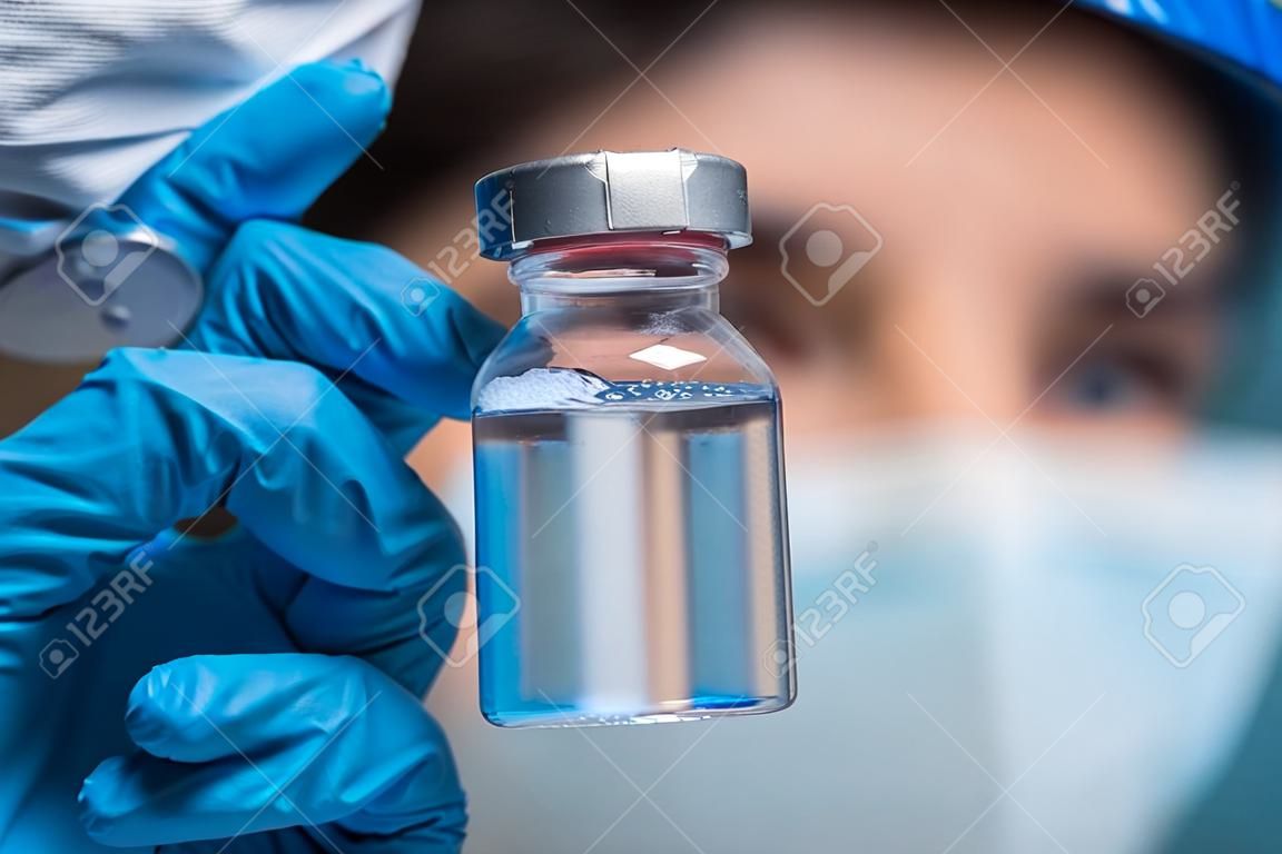 Doctor scientist with protective gloves and face mask holding vaccine medicine dose stock photo