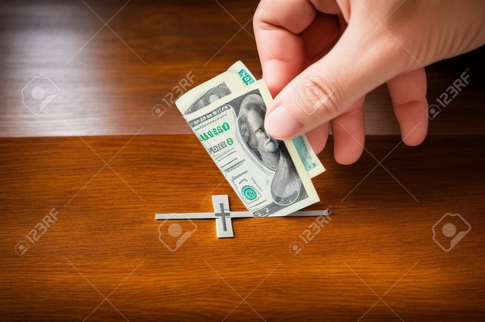 De mens steekt donatie in zijn hand met dollar in sleuf in de vorm van Christelijk kruis