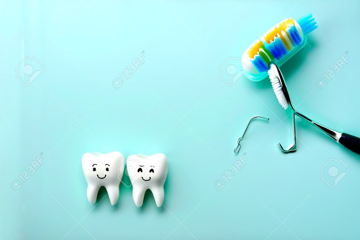 Zdrowe białe zęby uśmiechają się, a ząb z próchnicą jest smutny na zielonym miętowym tle. szczoteczka do zębów i narzędzia dentystyczne lustro, haczyk. skopiuj miejsce na tekst