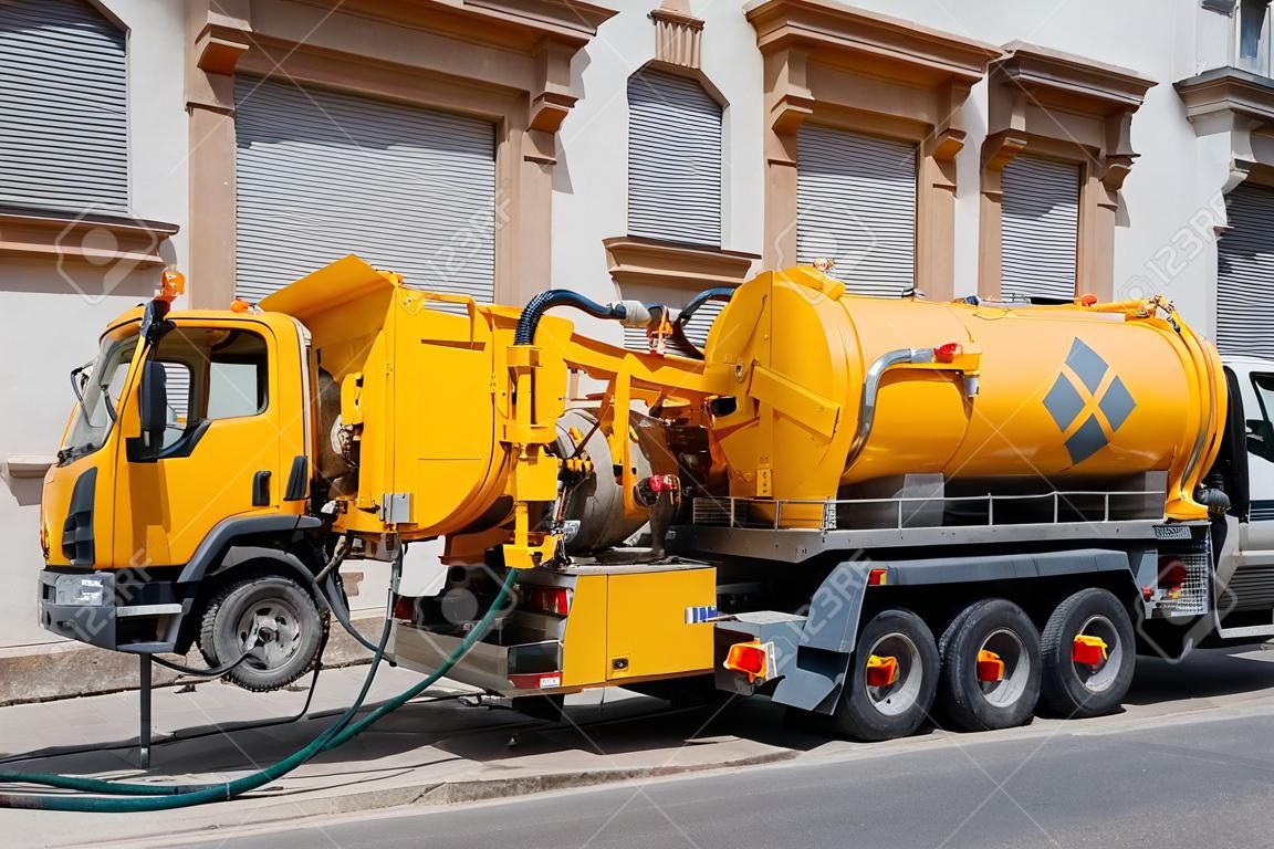 Канализация грузовик на улице работы - убирать канализации переполнения, уборка трубопроводов и потенциальные проблемы загрязнения от современного здания