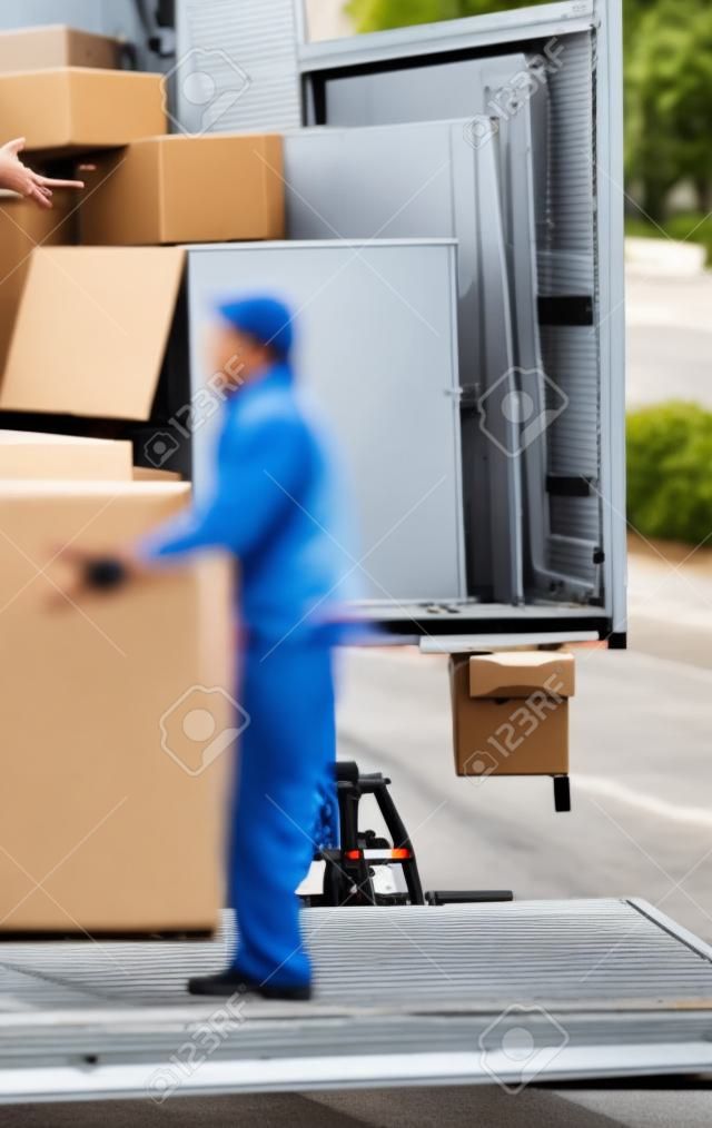 Man unloading boxes from truck by hand in the middle of a street - fast shipment goods delivery