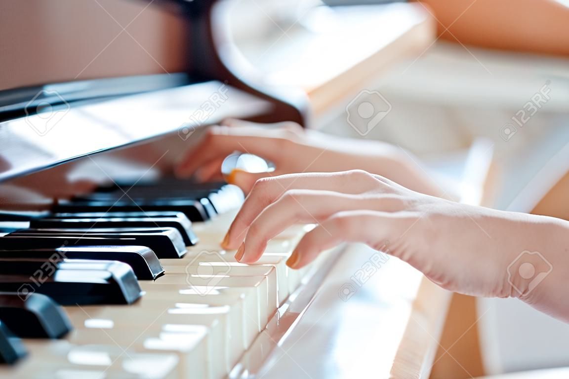 Female pianist hands on grand piano keyboard.