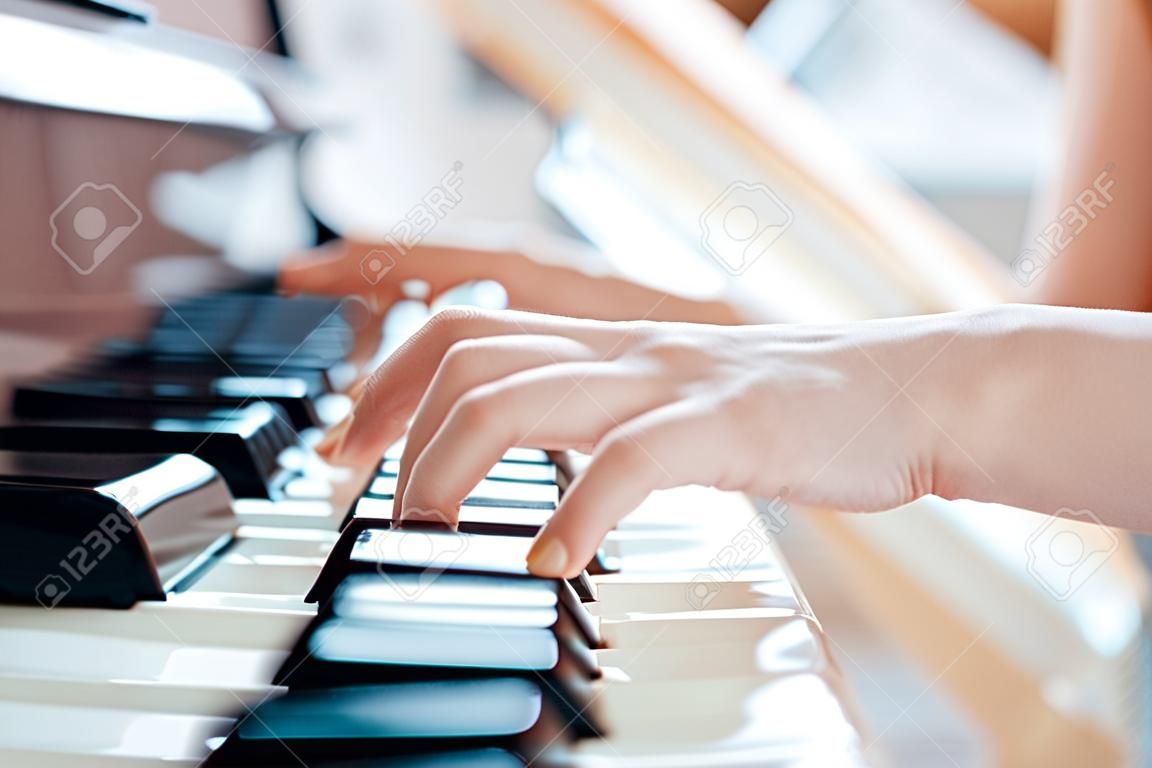 Mani femminili del pianista sulla tastiera del pianoforte a coda.
