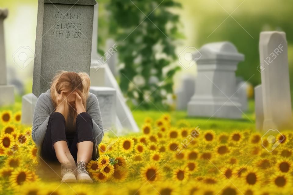 Lonely Crying Fiatal nő Gyász napraforgós előtt egy sírkő a temetőben