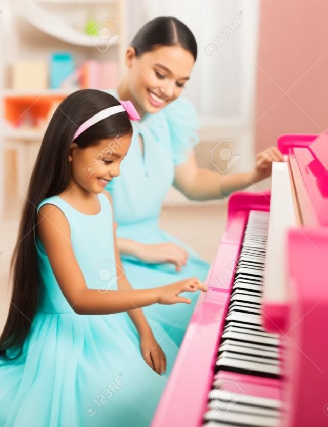 Dziewczynka uczy nauczyciel gry na pianinie. Koncepcja studiów muzyki i kreatywnego hobby