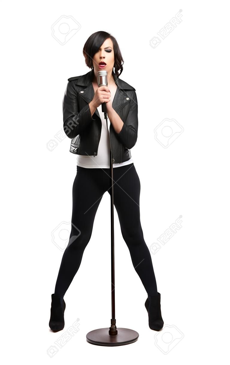 Full-length portrait of rock singer wearing leather jacket and keeping static mic, isolated on white. Concept of rock music and rave