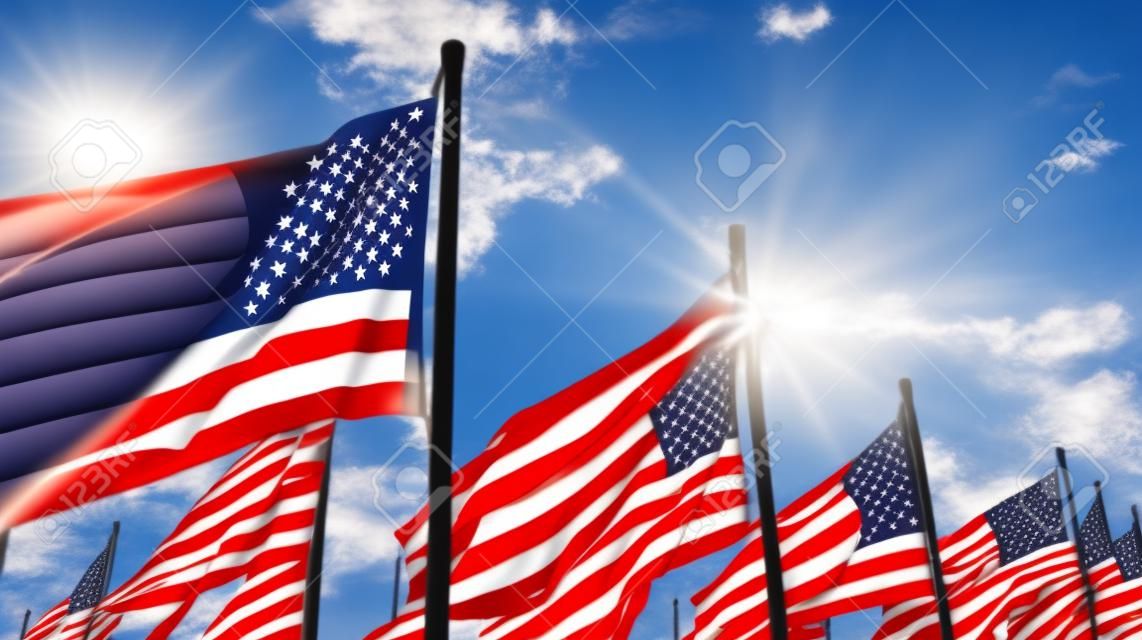 American flags flying in the wind against a blue sky with sun rays