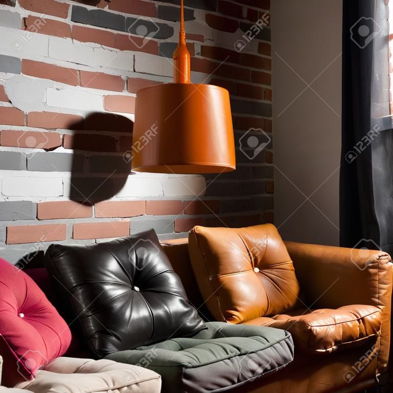 Colorful pillows on a sofa with brick wall in background