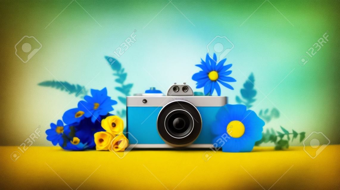 Retro camera met bloemen op gele en blauwe achtergrondkopieruimte