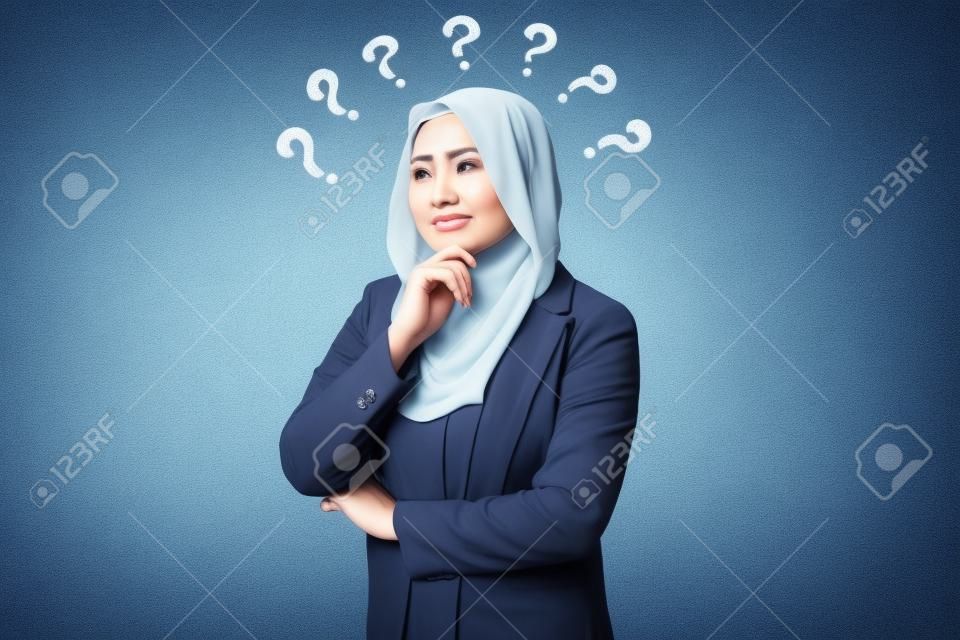 Mulher de negócios muçulmana asiática bonita que veste o hijab que olha para cima e que pensa com ponto de interrogação, mulher de negócios confundida de um problema, tentando encontrar a solução