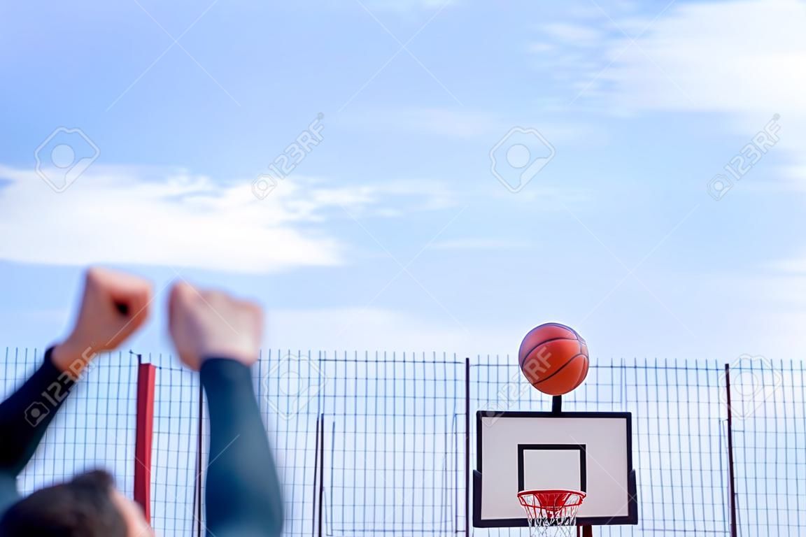 Homem atraente jogando basquete na quadra de basquete. O homem está fora de foco e em primeiro plano, fundo está no foco. Treinamento ao ar livre