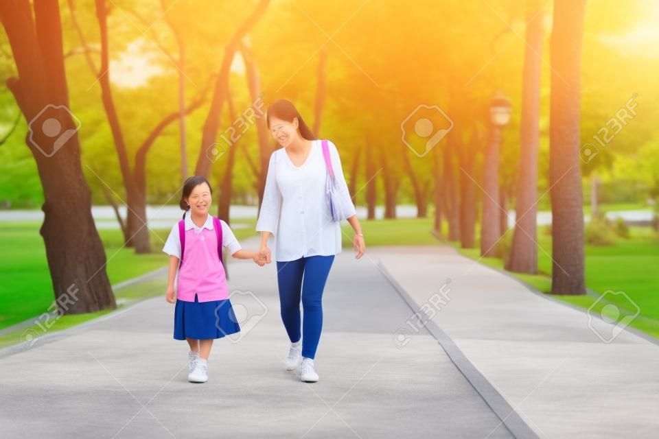 Asian mother and daughter student walking to school.