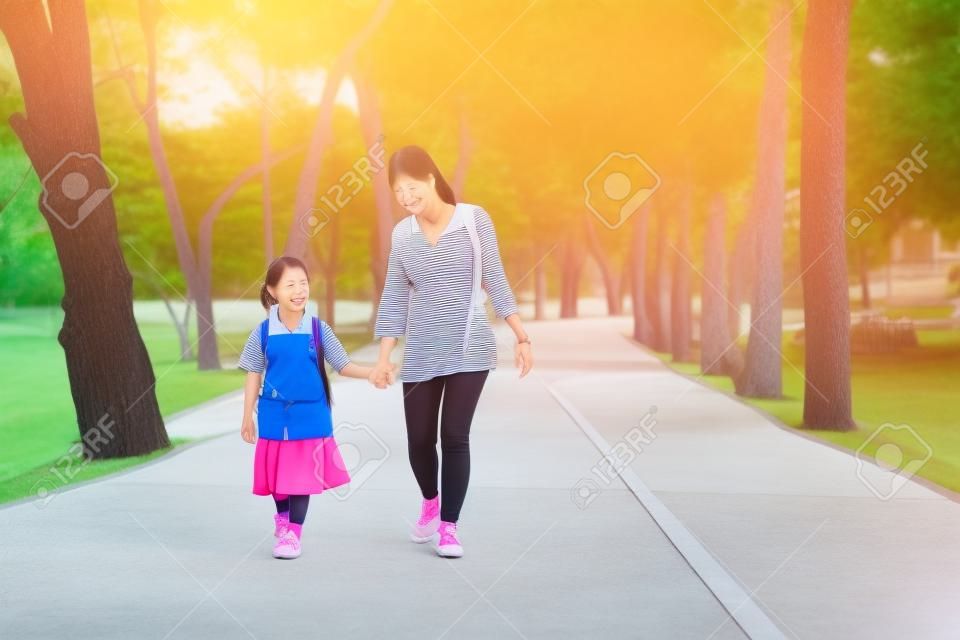 Asian mother and daughter student walking to school.