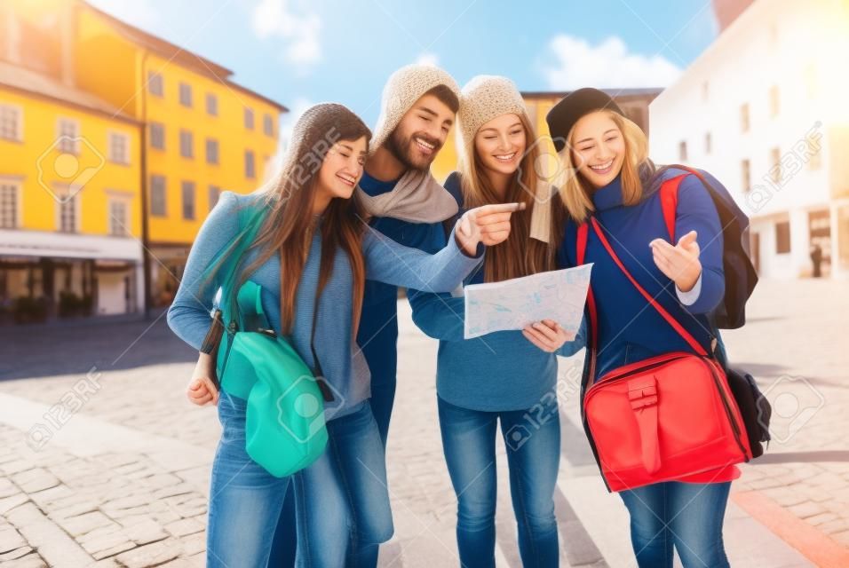 Csoport a turisták térkép - Párok legjobb barátok üdülési elveszett a régi központban - Fiatal diákok információt keresnek menetrendet a városi tér fogalma - barátság turizmus és az oktatás