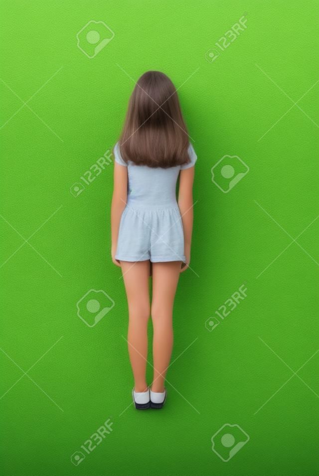 Widok z tyłu młoda dziewczyna z długimi włosami patrząc w ścianę. Na białym tle na zielonym tle