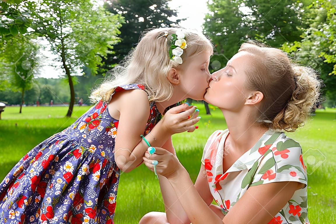 Hermosa chica besando a su madre en el parque