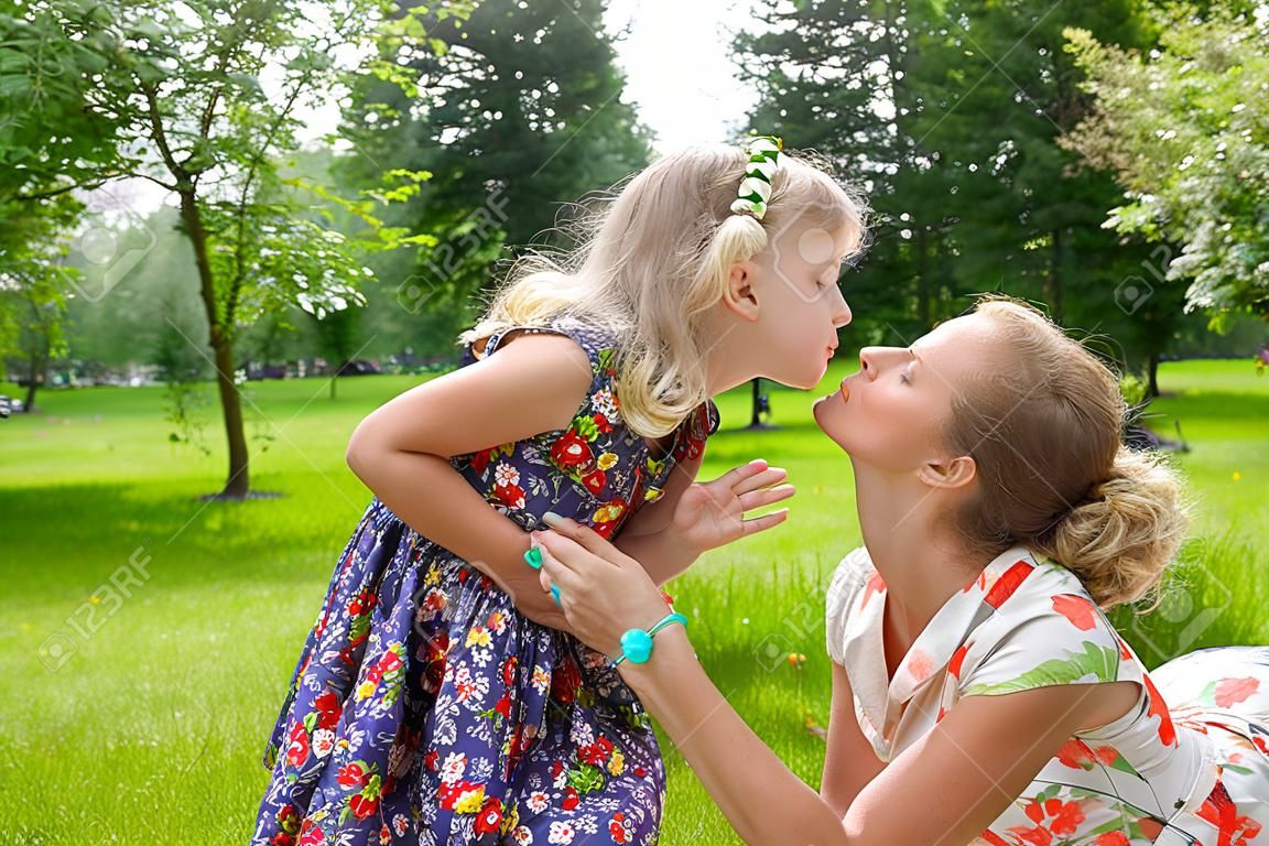 Hermosa chica besando a su madre en el parque