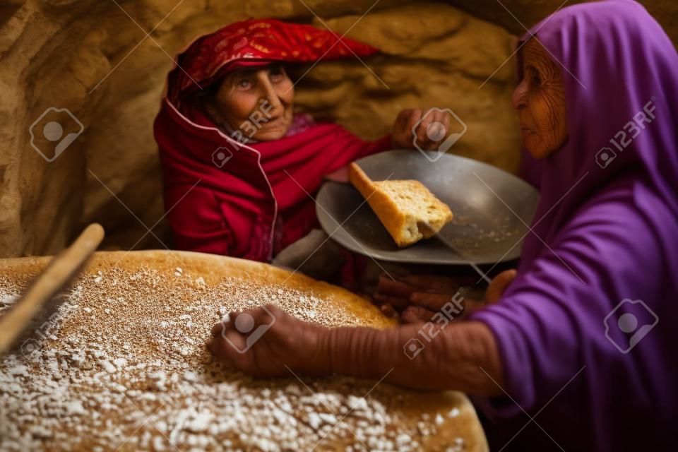 Vecchia donna araba prepara il pane in un villaggio beduino