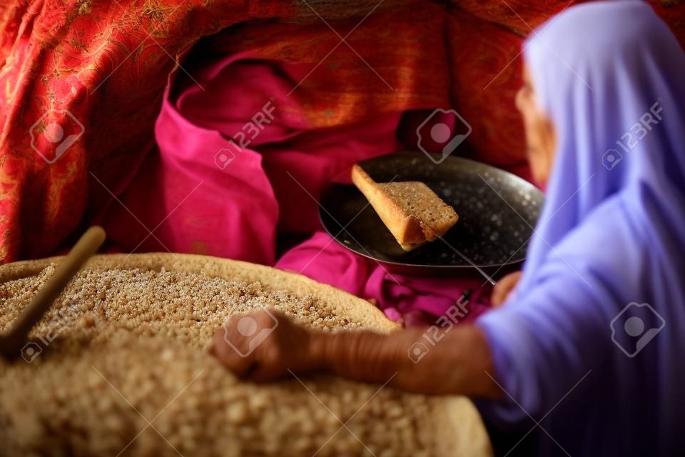 Vecchia donna araba prepara il pane in un villaggio beduino