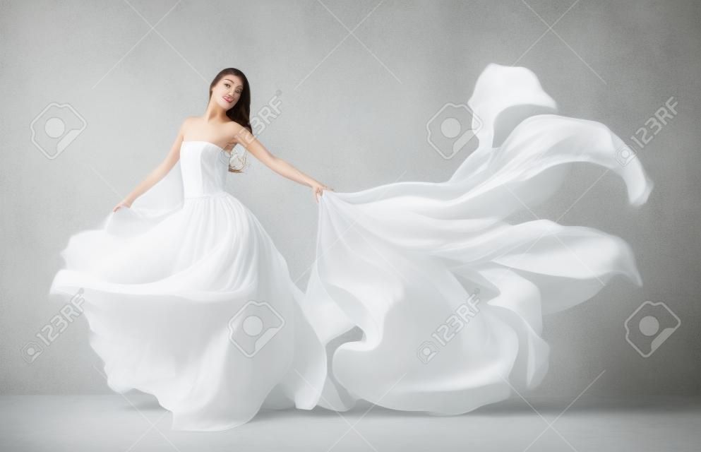 美丽的少女在飞行白色连衣裙流动织物