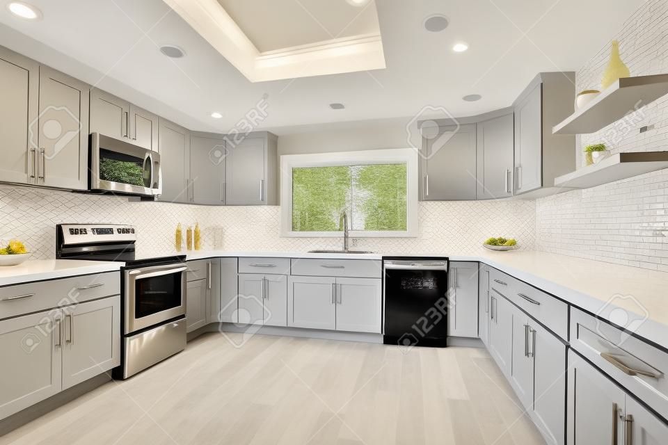 Cucina aperta con mobili bianchi, ripiani in quarzo grigio e alzatina piastrellata.