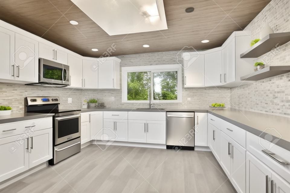 Cucina aperta con mobili bianchi, ripiani in quarzo grigio e alzatina piastrellata.