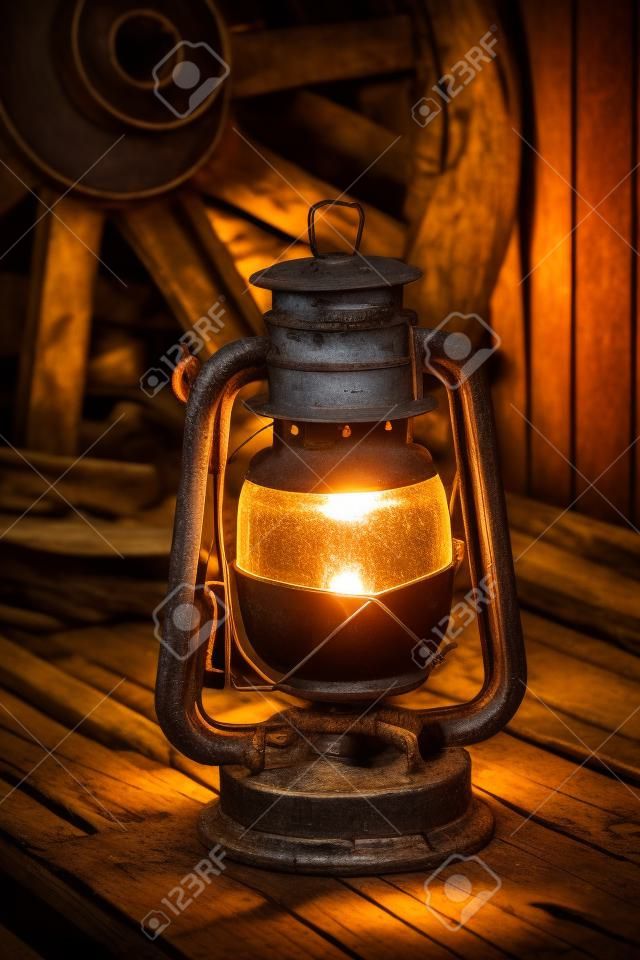 kerosene lamp on the old wooden boards against the background wagon wheel