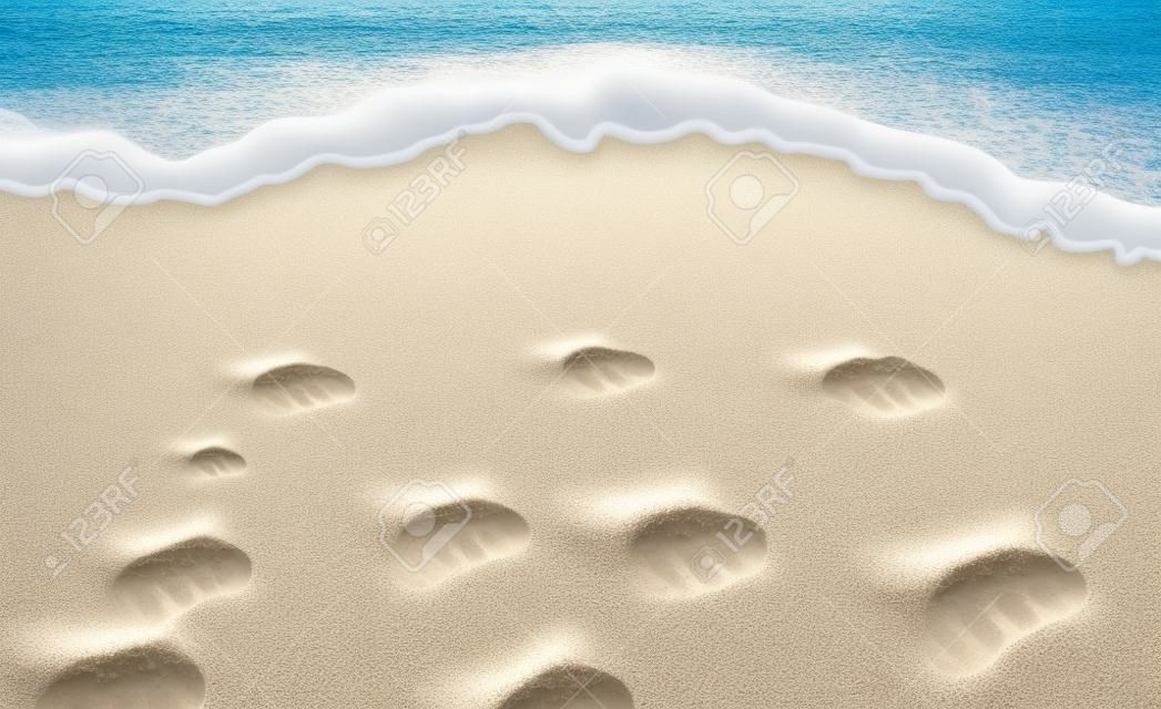 A sand and surf shoreline with foam and footprints