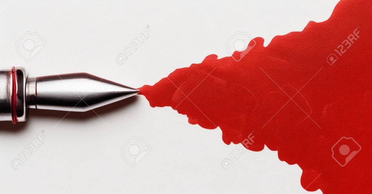 一个旧钢笔的金属笔尖的顶部，在一个孤立的白色背景下喷出一股厚厚的红墨水。