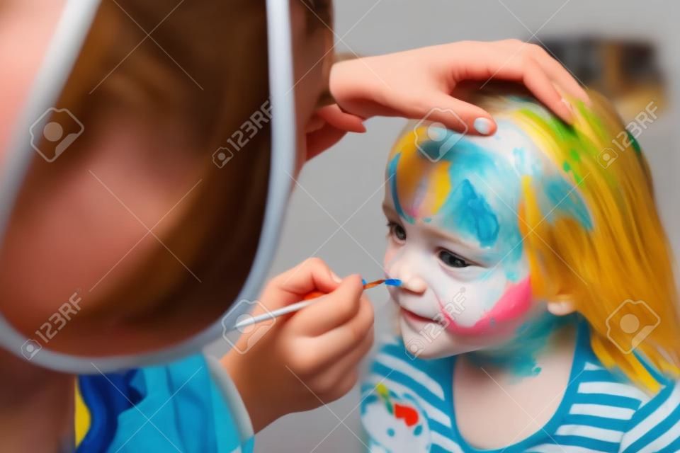 L'animateur peint le visage de l'enfant.