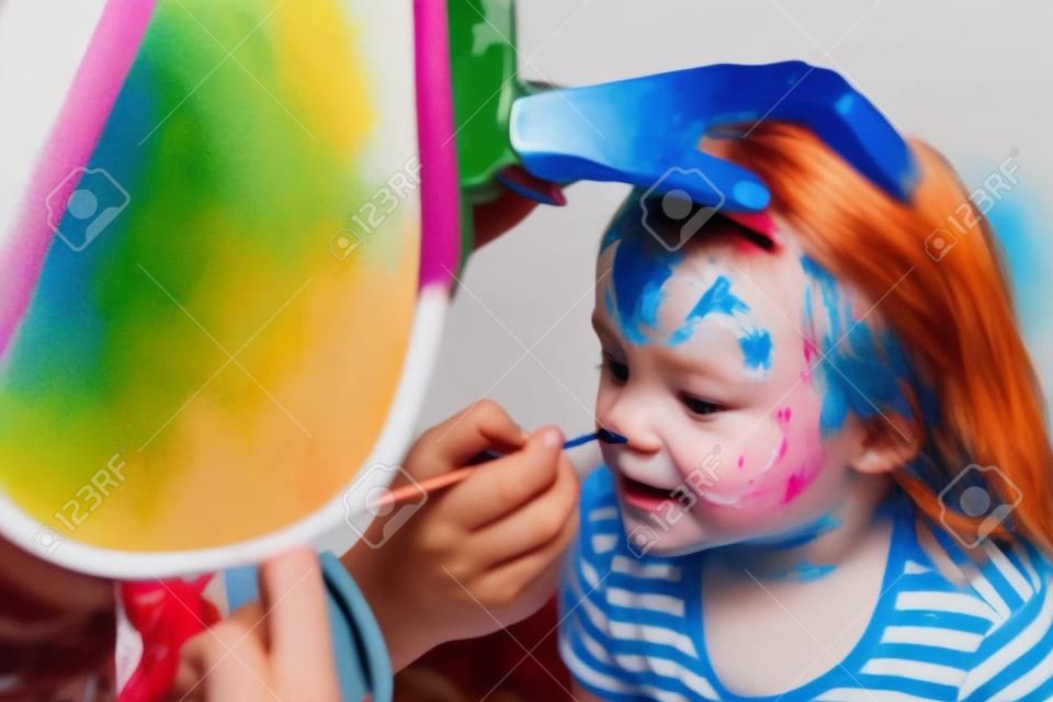 El animador pinta la cara del niño.
