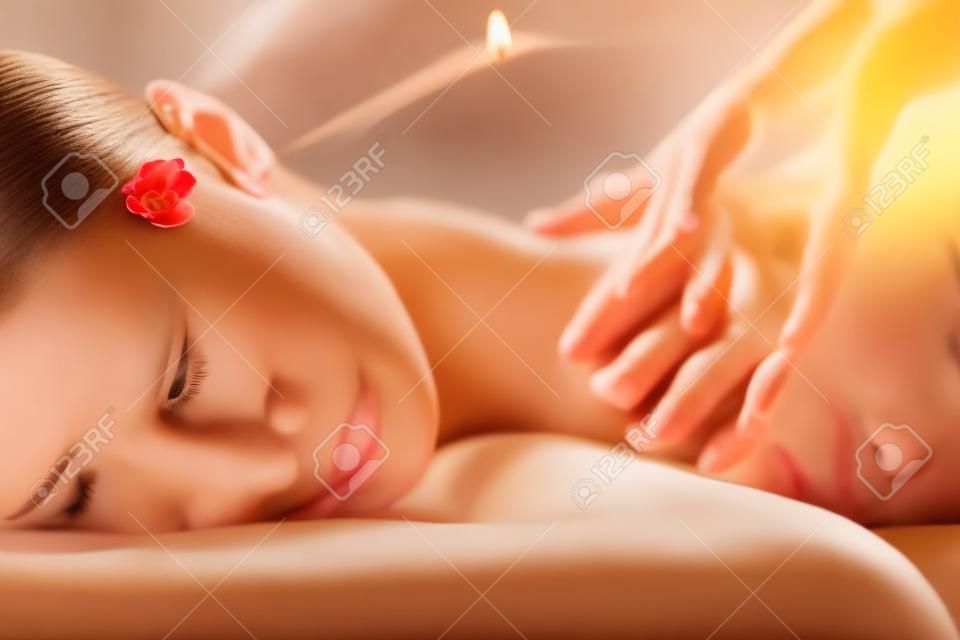Das schöne Mädchen hat eine Massage. Authentisches Bild einer luxuriösen Spa-Behandlung. Warme Farben, bezauberndes Licht.