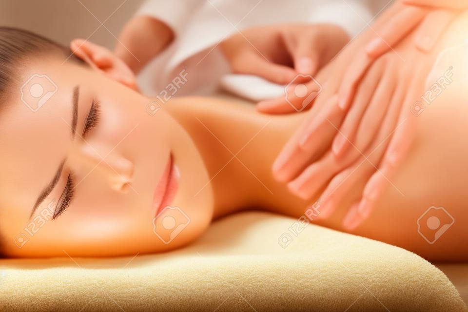 Das schöne Mädchen hat eine Massage. Authentisches Bild einer luxuriösen Spa-Behandlung. Warme Farben, bezauberndes Licht.