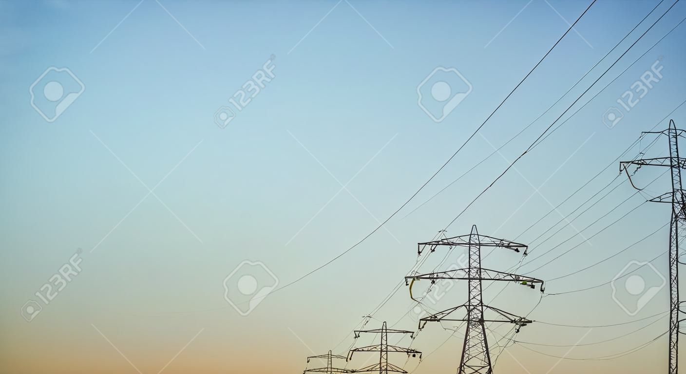La ligne électrique à haute tension s'élève contre les tours de transmission du ciel