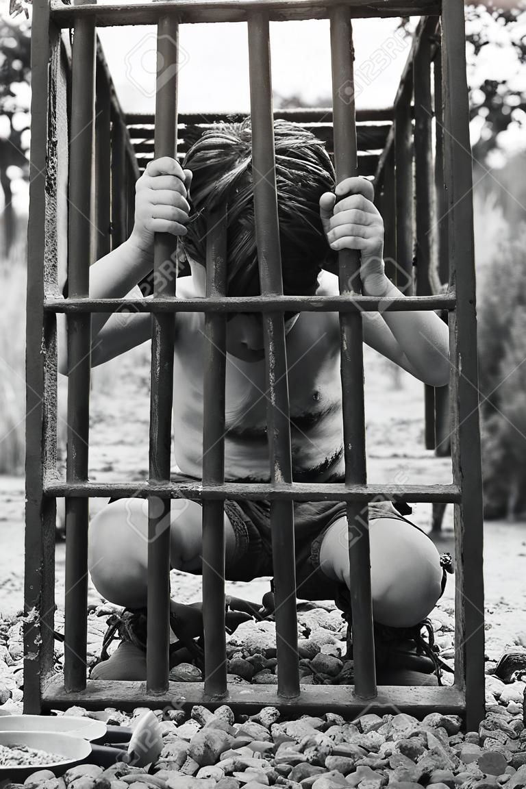소년은 감옥에 있습니다. 포획된 인간 아이. 납치와 인신매매의 개념.