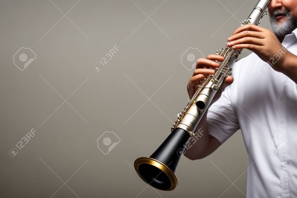 クラリネットのプレーヤーは、古典的な楽器を演奏手。白で隔離された木管楽器