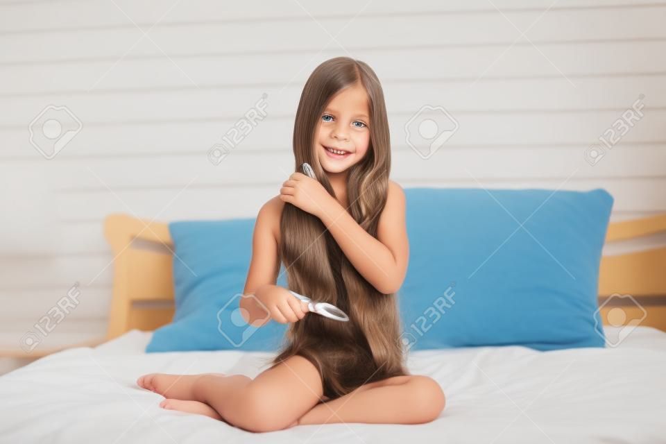 9 years old girl brushing her long hair in her bedroom in the morning