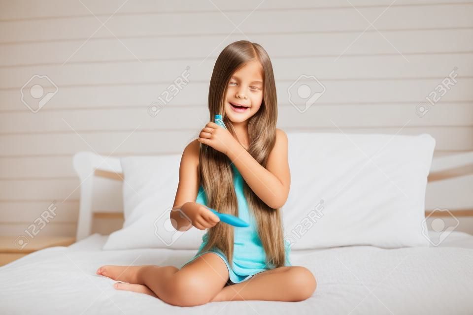 9 years old girl brushing her long hair in her bedroom in the morning